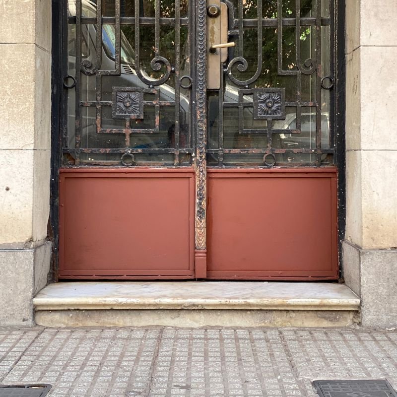 El marco está picado por la humedad — Restauración de puerta de entrada doble de hierro fundido. Cambio de las chapas inferiores comidas por la corrosión, conservando las molduras y los perfiles originales. Trabajo realizado por HERREELEC.